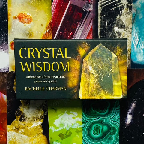 Crystal Wisdom kortų rinkinys ant tamsiai žalios dėžutės su ryškiu geltonu kristalu ir autorės Rachelle Charman vardu