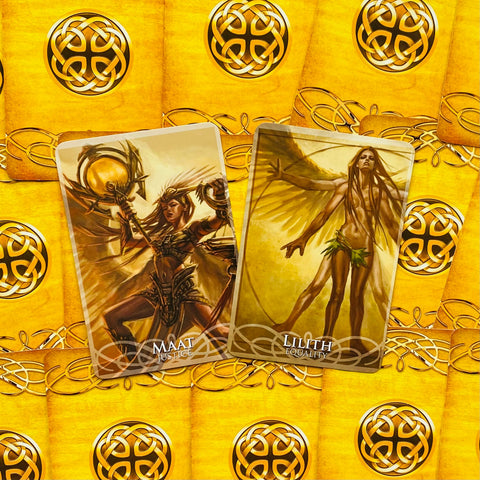 Tarot kortos aukso nugarėlėmis, dvi atverstos kortos Maat (Teisingumas) ir Lilith (Lyguma), matomos iš arti