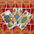 Tarot kortos Marseilio stiliaus, trys atverstos lazdų rūšies kortos išdėstytos kampu ant raudonų ornamentinių nugarėlių