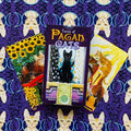 Tarot kortos Pagan Cats purpuriniame dėkle su juodos katės piešiniu, atidengtos trijų kortų fanu ant violetinio fono