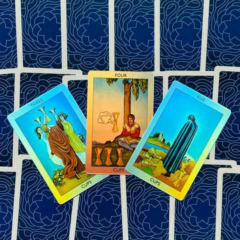 Tarot kortos Rider–Waite, trijų kortų išdėstymas (Trys, Keturi, Penki Taurių) ant mėlynos raštuotos nugarėlės