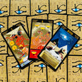 Tarot kortos su auksuotu Egipto dizainu, trys atverstos kortos fanuotos ant dėklo su ryškiomis mėlynomis akimis