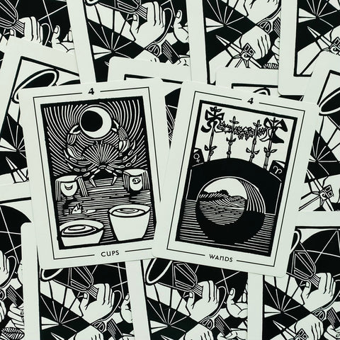 tarot kortos juodai baltos linorinės grafikos, atverstos 4 Taurių ir 4 Lazdų kortos parodytos ant raštuoto fono