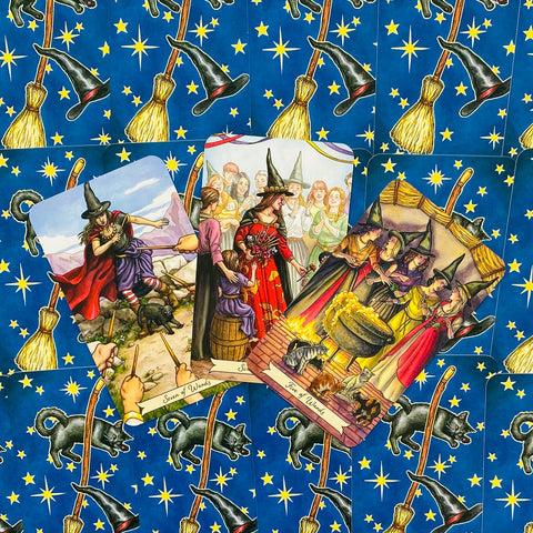 Tarot kortos su raganių iliustracijomis – trys atverstos kortos prieš mėlyną nugarėlių raštą, matomos priekinės iliustracijos