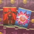 tarot kortos – dvi priekinės versijos: Chamunda (tamsiai raudona, gotikinė ikonografija) ir Nitya Kali (mėlyna–rožinė, žiedinė mandala), aiškūs dizainų skirtumai