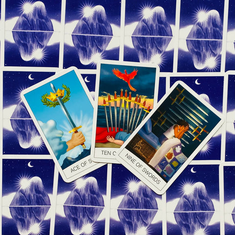 tarot kortos trijų kardų išklotinė: Ace, Ten ir Nine of Swords atverstos ant mėlynos žvaigždėtos nugarėlės