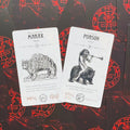tarot kortos baltos iliustruotos kortos Marax ir Purson ant raudonai juodų nugarėlių, artimas kampas pabrėžia detales