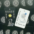 tarot kortos Orat Taro, dvi atverstos kortos: juoda su geltonu žiedu ir balta su mėlynu paukščiu