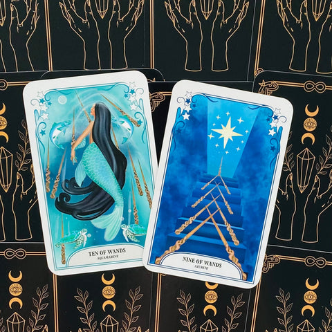 Tarot kortos Aquamarine ir Azurite: Dešimtukas ir Devintukas jūros mėlynomis iliustracijomis ant juodo dėklo su aukso raštais