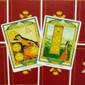 Tarot kortos — dvi atviros kortos (Three of Coins, Four of Coins) su raudonomis nugarėlėmis ir auksine karūnos dekoracija