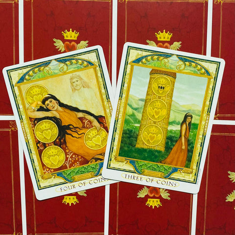 Tarot kortos — dvi atviros kortos (Three of Coins, Four of Coins) su raudonomis nugarėlėmis ir auksine karūnos dekoracija