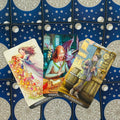 Tarot kortos — Pentaklių rinkinys: trys atverstos kortos (Karalienė, Riteris, Puslapis) ant mėlyno žvaigždėto nugarėlio, artimas kampas