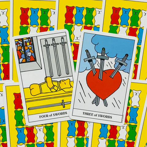 Tarot kortos ryškiais geltonais nugarėlėmis, atverstos į „Trys kalavijai“ ir „Keturi kalavijai“ iliustracijas