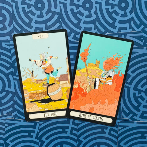tarot kortos dviejų kortų išklotinė — The Fool ir King of Wands, ryškūs motyvai ant mėlyno raštuoto fono, kampu sustatyta ir kortų pavadinimai matomi