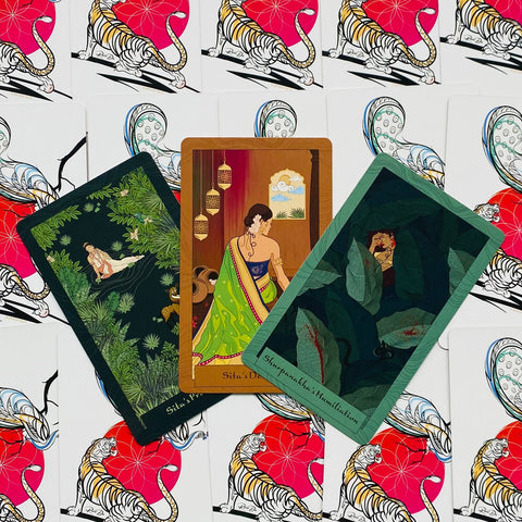 tarot kortos trijų atvirų iliustruotų kortų komplekte — centre moteris žaliame sari, šone lapų tamsios scenos ir dekoruoti kortų nugarėlių tigrai