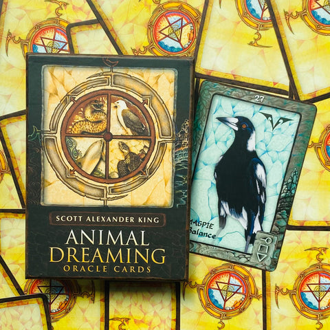 Orakulo kortos Animal Dreaming dėžutėje (Scott Alexander King), šalia atversta varnos/šnibždėtojos korta ant geltono simetriško fono