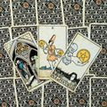 Tarot kortos Rider–Waite stiliaus, trys priekinės kortos (Ace, Two, Three of Pentacles) išdėstytos ant raštuotų nugarėlių, matomas detalus priekinis dizainas ir spalvos
