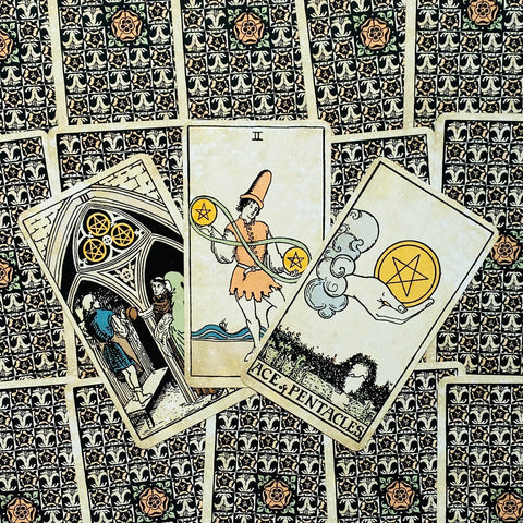 Tarot kortos Rider–Waite stiliaus, trys priekinės kortos (Ace, Two, Three of Pentacles) išdėstytos ant raštuotų nugarėlių, matomas detalus priekinis dizainas ir spalvos