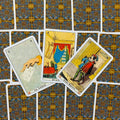 Tarot kortos komplektas su ornamentuotomis auksinėmis ir mėlynomis nugarėlėmis, kompozicija trijų atverstų kortų rodoma iš viršaus