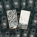 tarot kortos juodai baltos su auksiniu apvadu, dvi atverstos kortos (akių motyvas ir trikampis) ant nugarėlių su saulėmis ir ratais