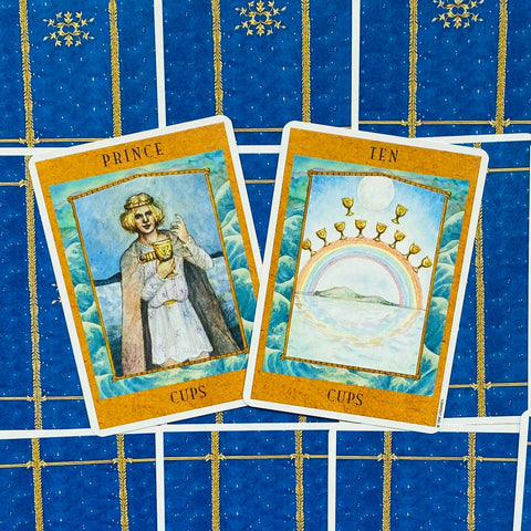 tarot kortos – atviros „Prince“ ir „Ten of Cups“ kortos su gintaro rėmais, pakryžiuotos ant mėlyno nugarėlių rašto