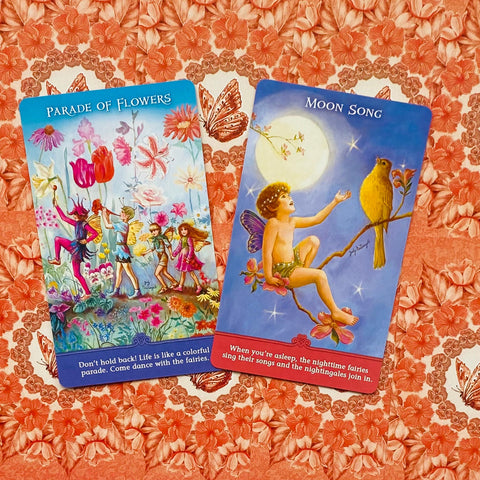 Orakulų kortos su pasakų motyvais, dvi spalvingos kortos (Parade of Flowers ir Moon Song) ant ryškaus gėlių fono