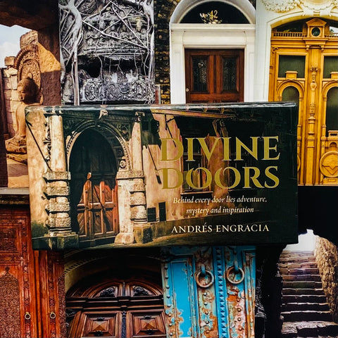 knyga Divine Doors kietu viršeliu su auksiniais užrašais ir architektūrinėmis durų iliustracijomis, rodoma iš priekio