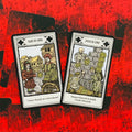 tarot kortos su monetų rūšimi, dvi atverstos kortos — Aštuoni ir Septyni monetų, padėtos ant ryškiai raudonos nugarėlės