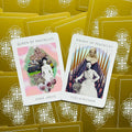 Tarot kortos — dvi atvertos Pentaklių kortos (Queen, Knight) ant auksinių nugarėlių su rožinėmis ir pastelinėmis spalvomis