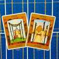 Tarot kortos dvi atverstos Staves (Three ir Four) kortos ant mėlyno ornamentuoto nugarėlio, pasuktos skirtingais kampais