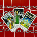 Tarot kortos su raudonomis nugarėlėmis, arti trijų kortų – Lazdų dvejkos, trejkos ir ketverto priekiai