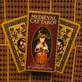 Medieval Cat Tarot stalo kortų rinkinys (Lawrence Teng) su raudona–auksine dėže ir dviem išskleistomis nugarėlėmis, skirtas taro praktikoms ir kolekcijai