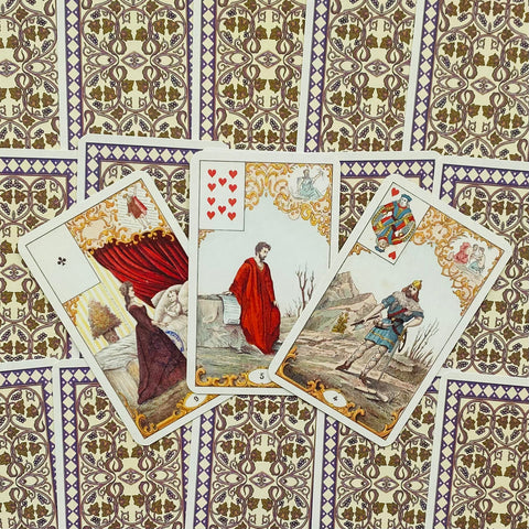 tarot kortos su vintažinėmis iliustracijomis, trys atvertos kortos per kraštą išdėstytos ant violetinio ornamentuoto fono