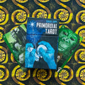 Tarot kortos Primordial (Sergio Toppi) mėlynoje dėžutėje centre, šone atvertos žalios kortos ant geltonai‑juodo spiralinio rašto