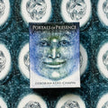 Kortų kaladė Portals of Presence (Deborah Koff‑Chapin), mėlyna mistinė veido iliustracija, fotografuota iš viršaus ant raštuoto fono