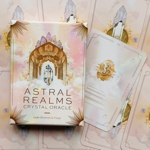 Astral Realms kortų rinkinys pastelinėje rožinėje pakuotėje su kristalų motyvu ir viena kampu atversta korta