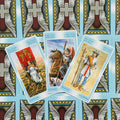Tarot kortos, atverstos mėlyna nugarėle — Lazdų kostiumo Karalienė, Riteris ir Pustonis, kampu išdėstytos, parodytos prie dekoratyvinių nugarėlių