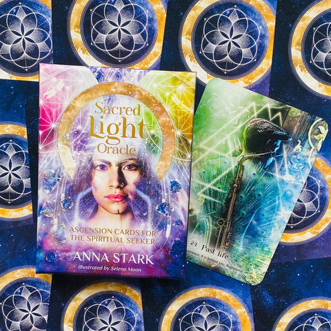Orakulo kortos Sacred Light Anna Stark — spalvotas dvasinis kortų rinkinys su atversta Past life korta ir ornamentuotu fonu