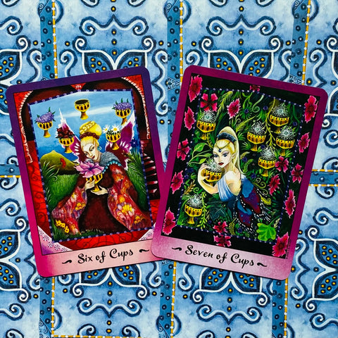 Tarot kortos su šešių ir septynių taurių iliustracijomis, ryškiai violetinėmis kraštinėmis, pasvirusiu kampu ant mėlyno raštuoto fono