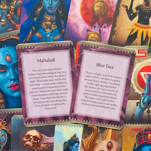 Taro kortos – artimas planas su atvertomis Mahakali ir Blue Tara kortomis ant spalvingo iliustruotų kortų fono, leidžia pamatyti tekstus ir dizainą