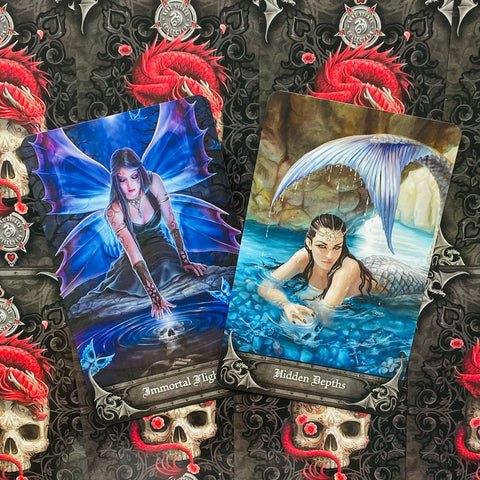 tarot kortos — dviejų kortų art box, mėlyna fėja (Immortal Flight) ir undinė (Hidden Depths) matomos iš viršaus ant juodo kaukolės fono