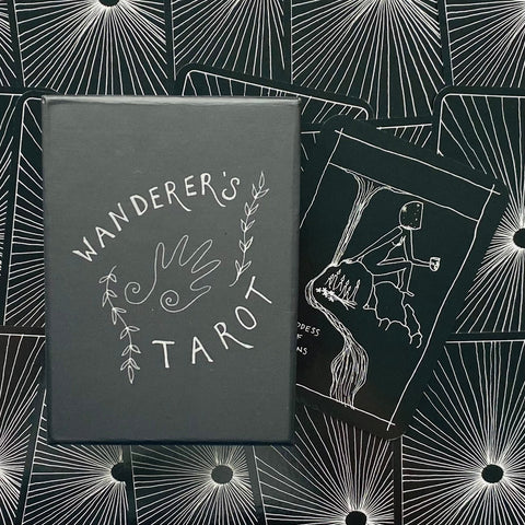 Tarot kortos juodoje dėžutėje su baltu „Wanderer's Tarot“ logotipu ir minimalistinėmis juodai baltomis kortomis