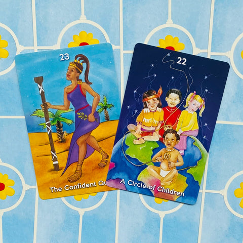 Kortos: spalvingos orakulo kortos su The Confident Queen (23) ir A Circle of Children (22) ant mėlyno rašto fono