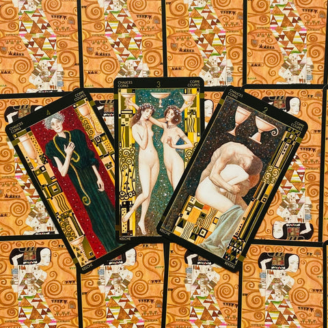 Tarot kortos Taurių komplektas — trys atverstos kortos su Klimto tipo ornamentika ir raštuotomis nugarėlėmis