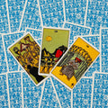 Tarot kortos rinkinys su ryškiomis taurų kortomis ir mėlynomis nugarėlėmis, trijų kortų išklotinė rodoma