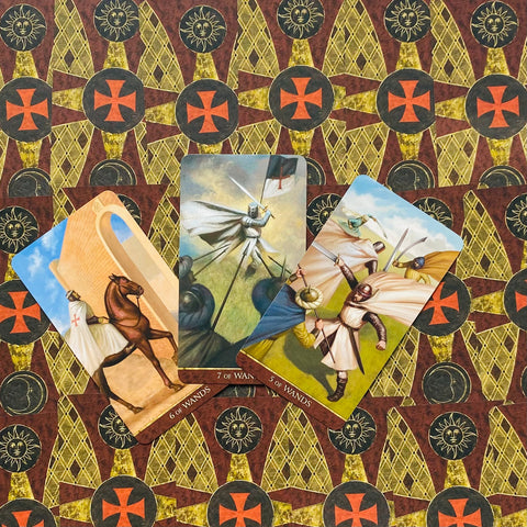 Tarot kortos rinkinys su trimis išskleistomis riterių kortomis ir raštuota raudona‑auksine nugarėle, skirtas taro skaitymams