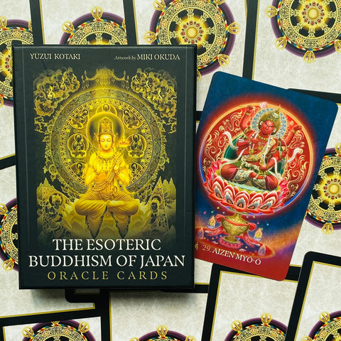 Orakulo kortos The Esoteric Buddhism of Japan juodoje dėžutėje su auksiniu Budos piešiniu, šalia raudona Aizen Myō‑ō korta, rodanti kitą variantą galerijoje