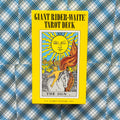Giant Rider–Waite tarot kortų rinkinys geltoname dėkle su „The Sun“ kortos viršeliu, frontinis vaizdas ant mėlyno languoto fono