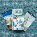 tarot kortos Tarot of the Dream Enchantress su dėžute ir dviem išskleistomis kortomis ant turkio‑violetinio raštuoto audinio
