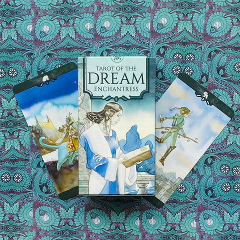 tarot kortos Tarot of the Dream Enchantress su dėžute ir dviem išskleistomis kortomis ant turkio‑violetinio raštuoto audinio